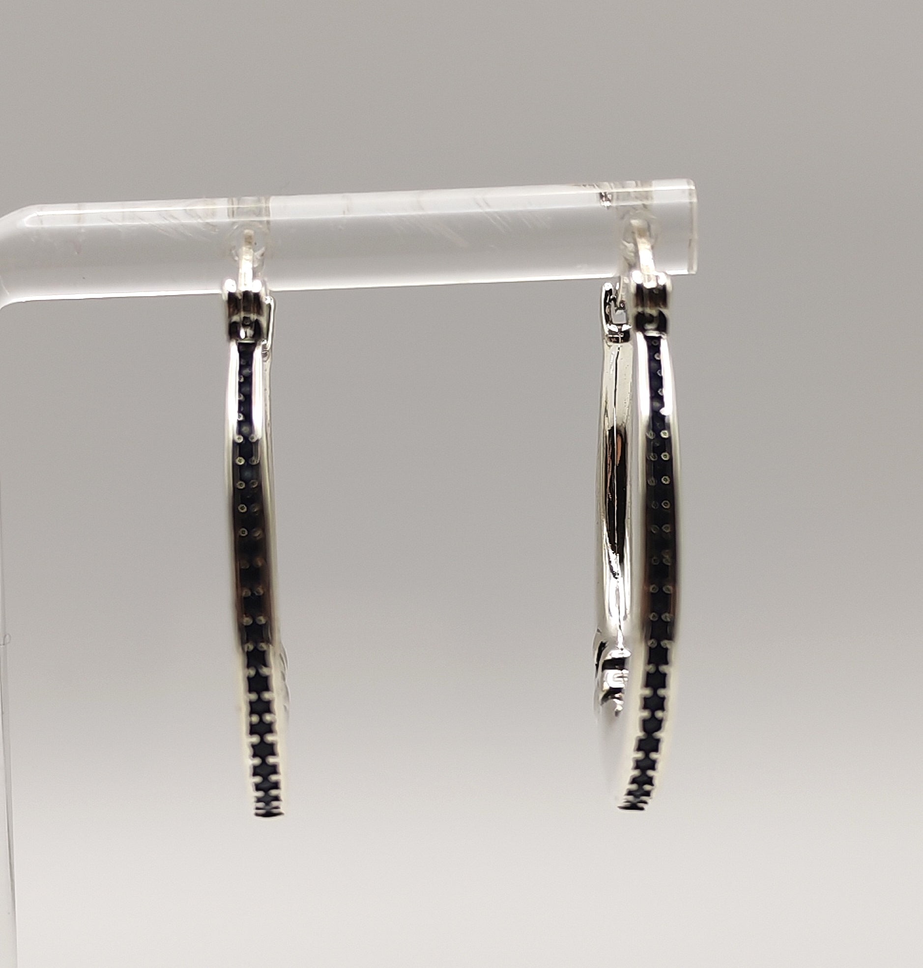 Sterling silver half moon hoop earrings on a clear stand showing front view of blue zirconia's.