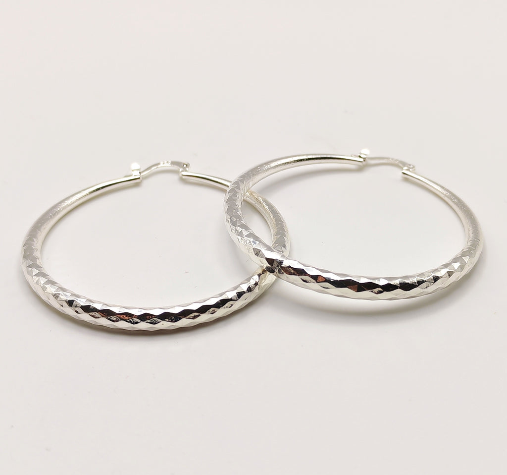 Polished silver hoop earrings with faceted diamond-cut detailing
