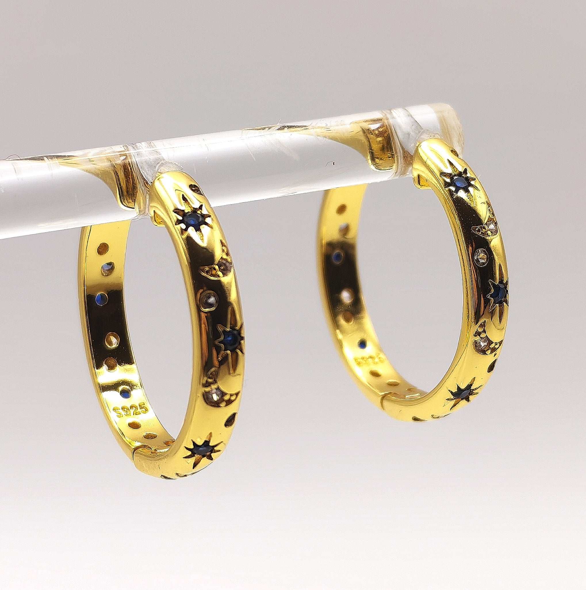 Side angle of celestial gold hoop earrings highlighting star engravings and sparkling zirconia's.