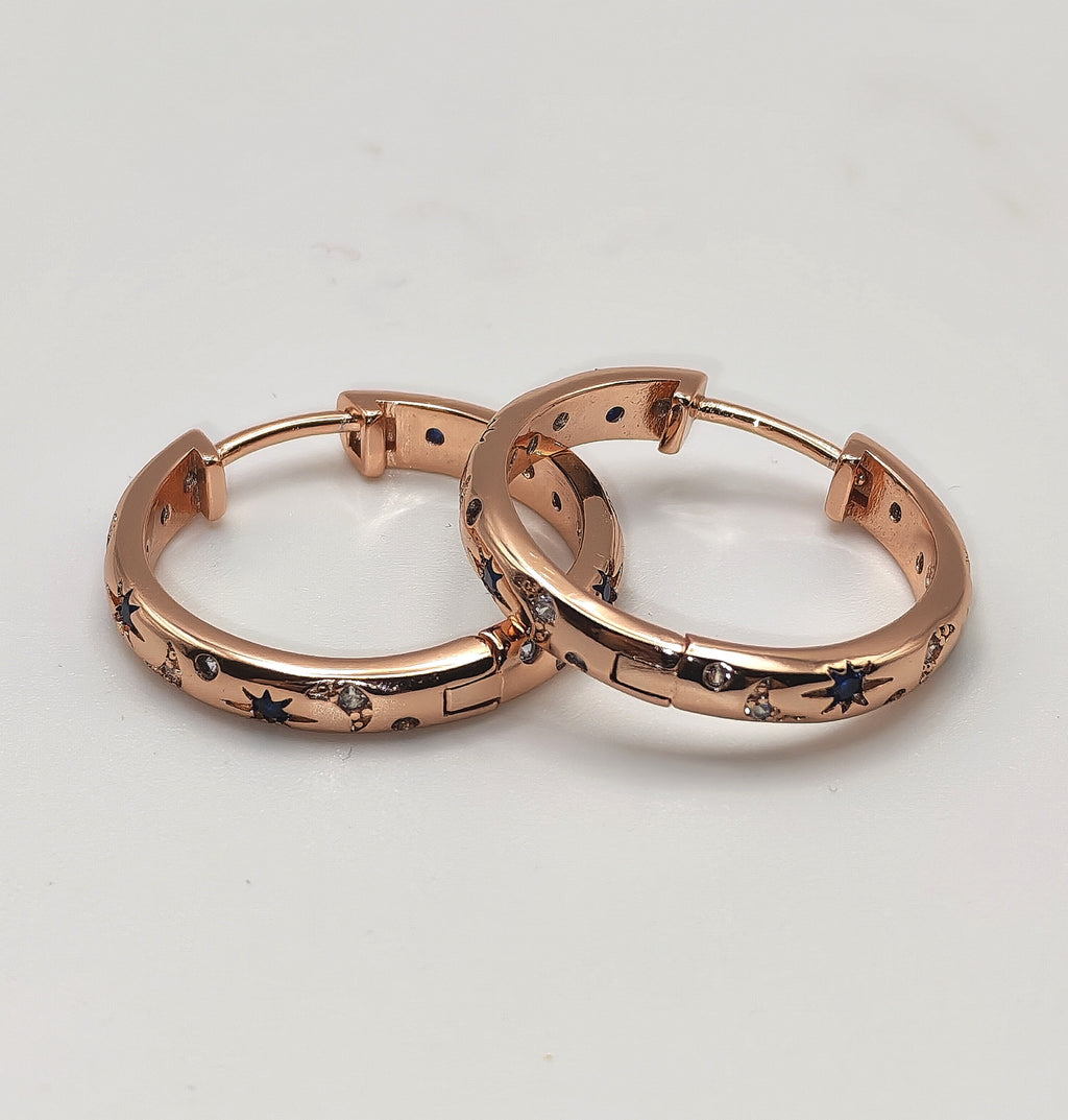 Rose gold plated sterling silver hoop earrings with blue and white zirconia's displayed on a white background.
