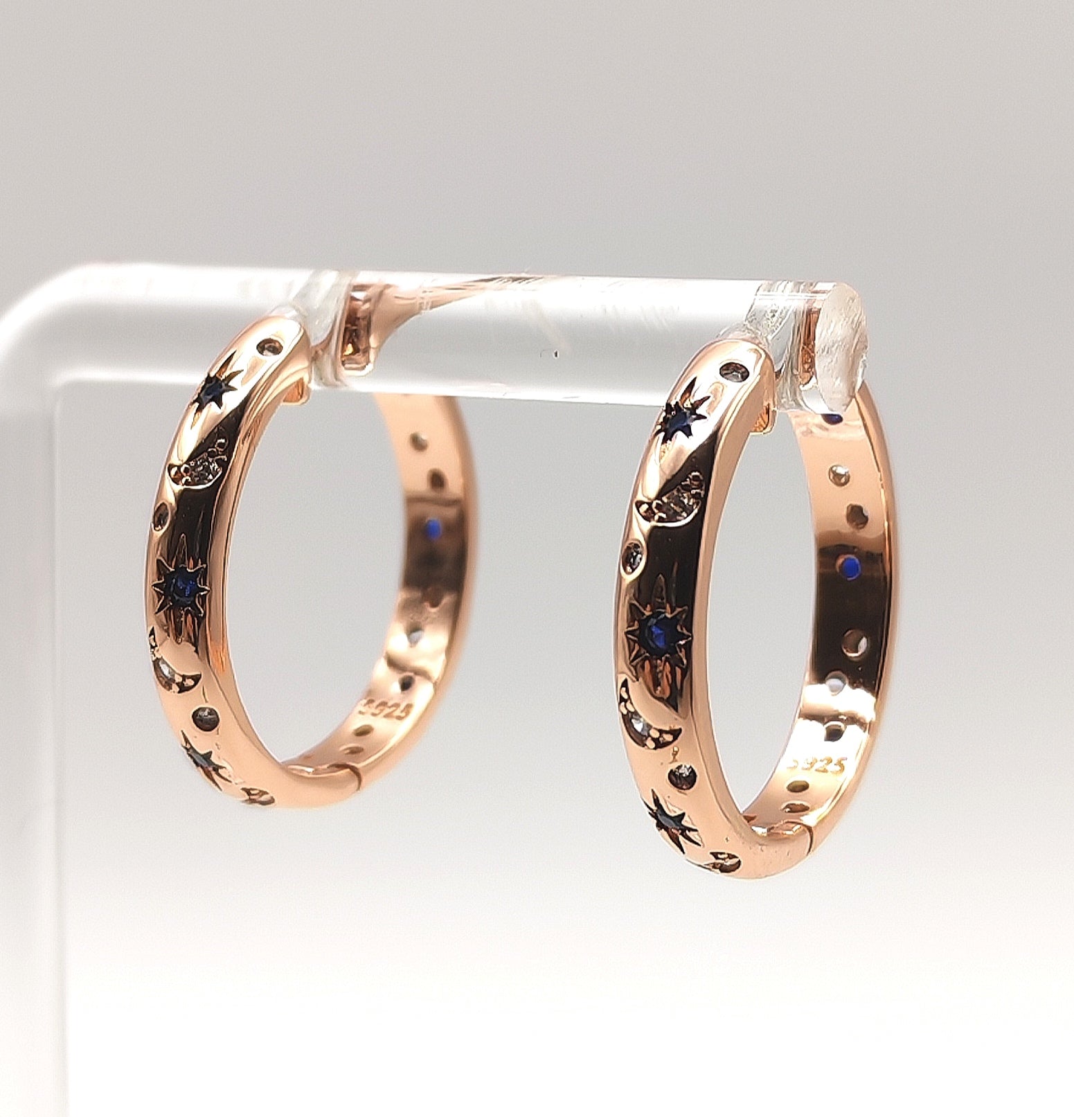 Side angle of rose gold hoop earrings highlighting engraved star motifs and sparkling zirconia's.