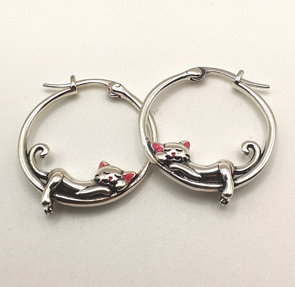 Macro shot highlighting the fine detailing of the sterling silver sleeping cat on the hoop earring.