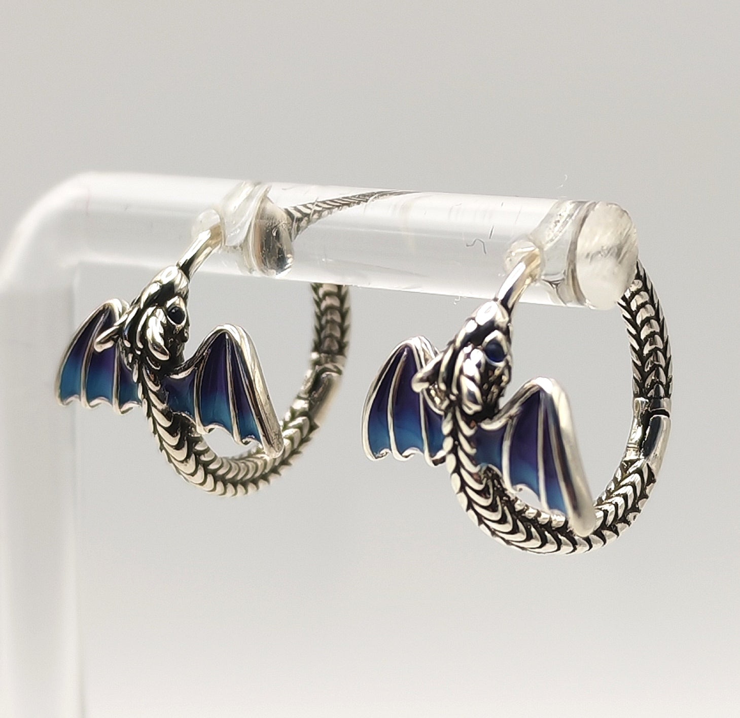 Side view of silver dragon hoop earring highlighting curved tail and wing enamel