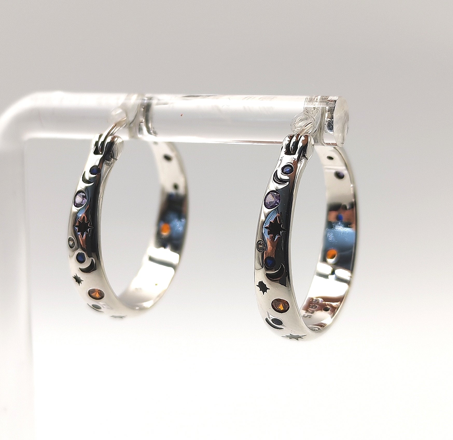 Side view of sterling silver hoop earrings with celestial moon and star engravings