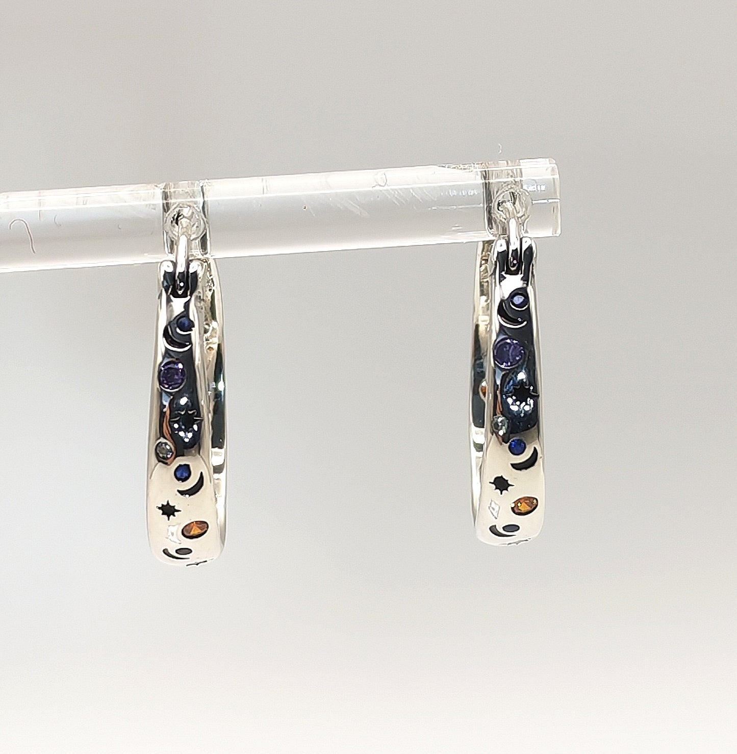 Sterling silver celestial hoop earrings photographed on a white background.