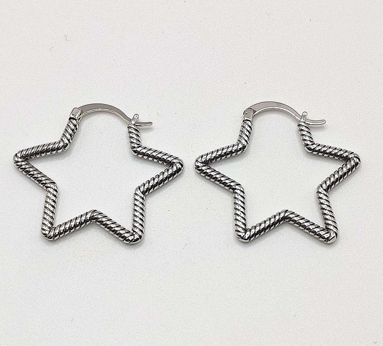 Open star-shaped sterling silver hoop earrings on white background
