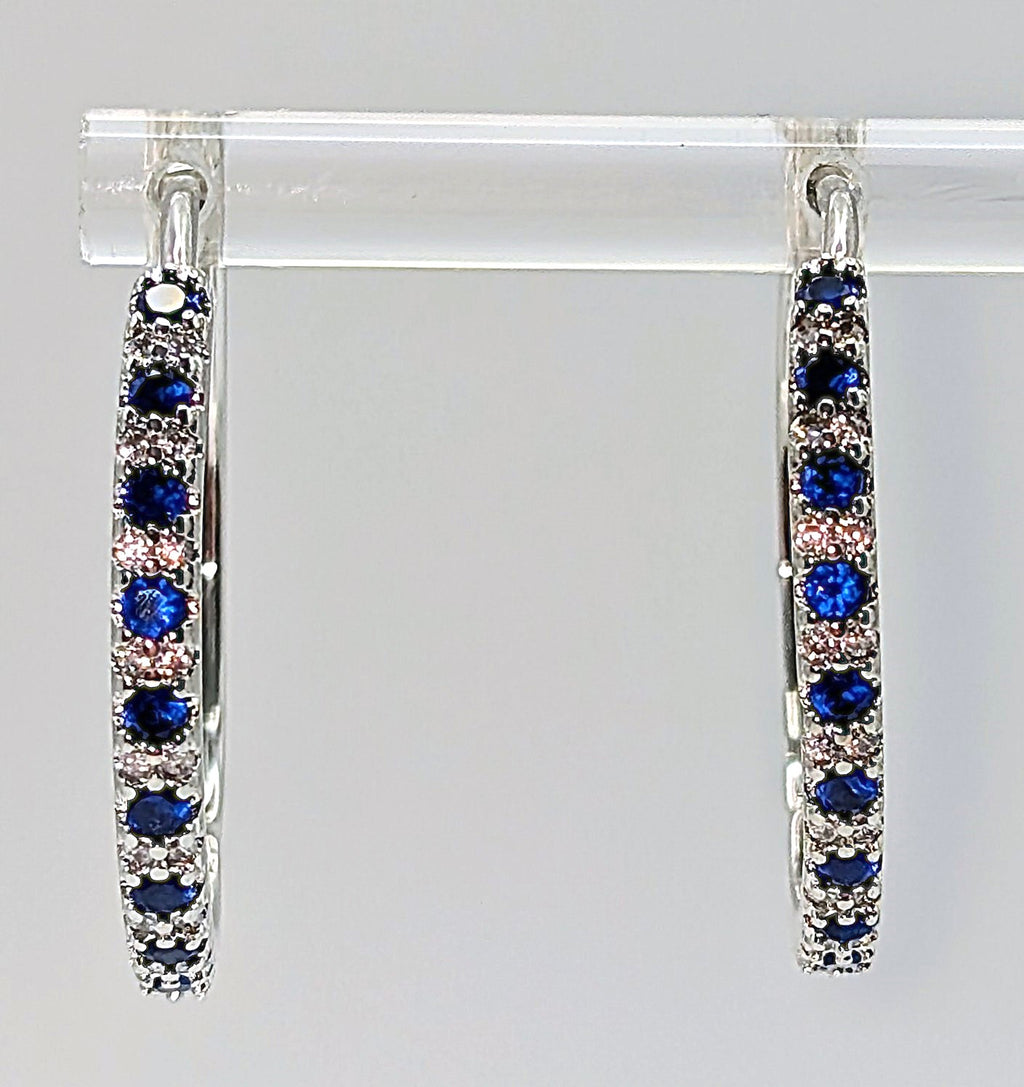 Sterling silver hoop earrings with blue and clear zirconia stones on white background