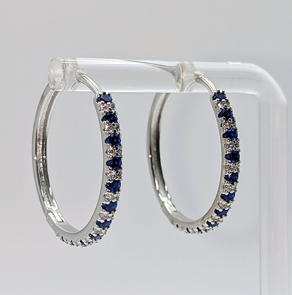 Sterling silver hoop earrings with blue and clear zirconia stones on white background