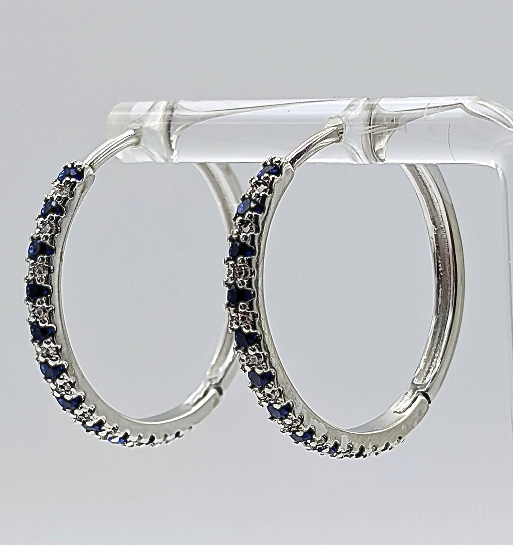 Side view of sterling silver zirconia hoop earrings with blue stones