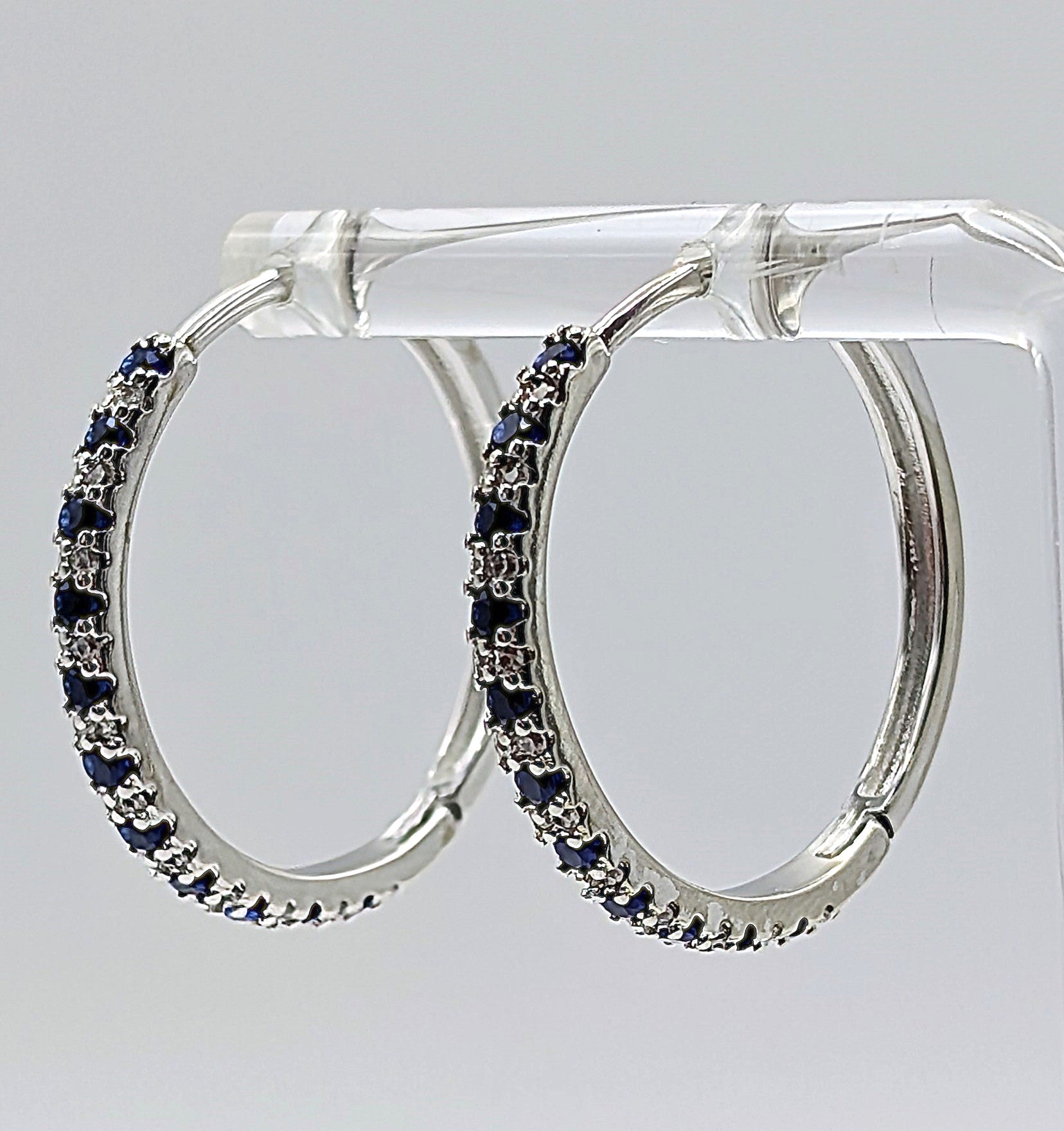 Side view of sterling silver zirconia hoop earrings with blue stones