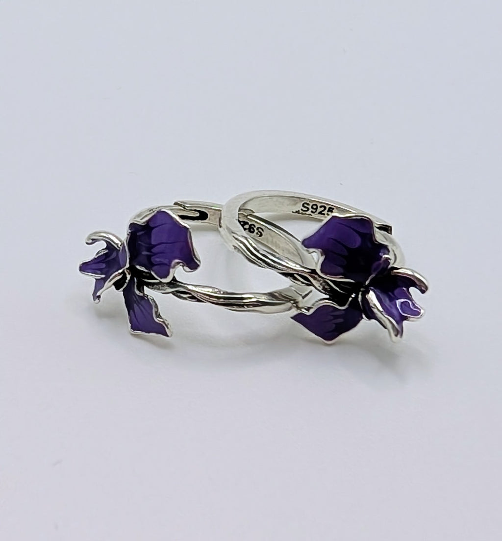 Close-up of purple iris enamel flower on silver hoop earring