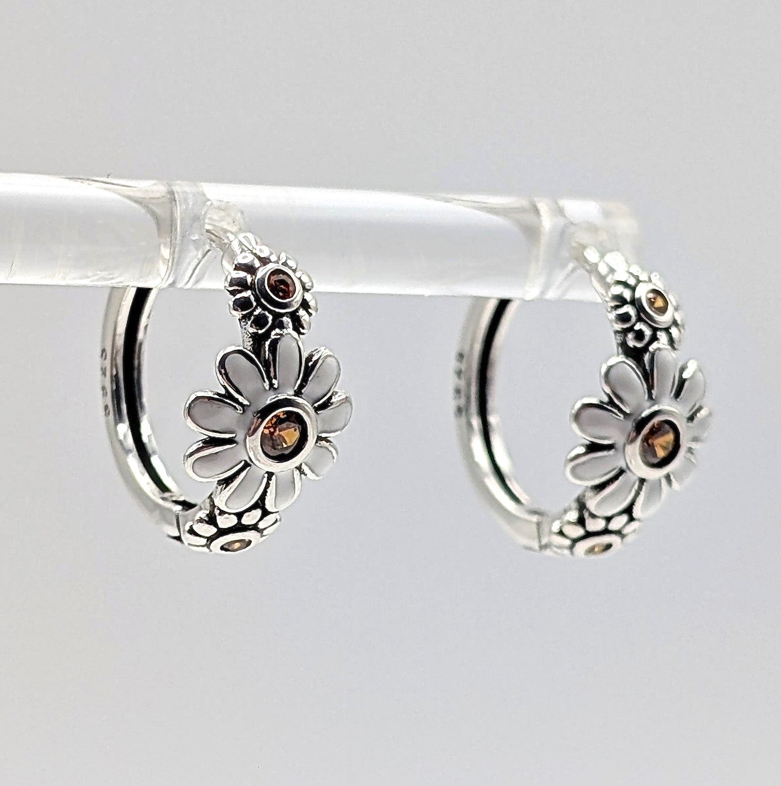 Side view of sterling silver daisy hoop earrings with zirconia stones