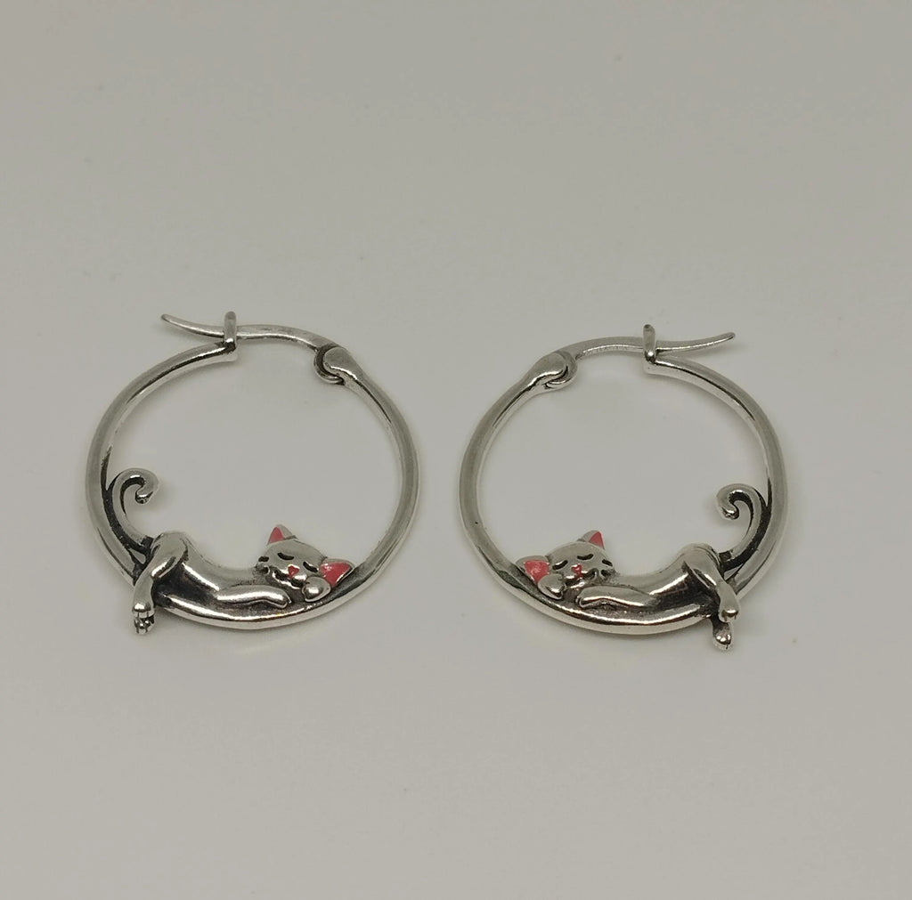 Silver hoop earrings with cat designs on a light gray background